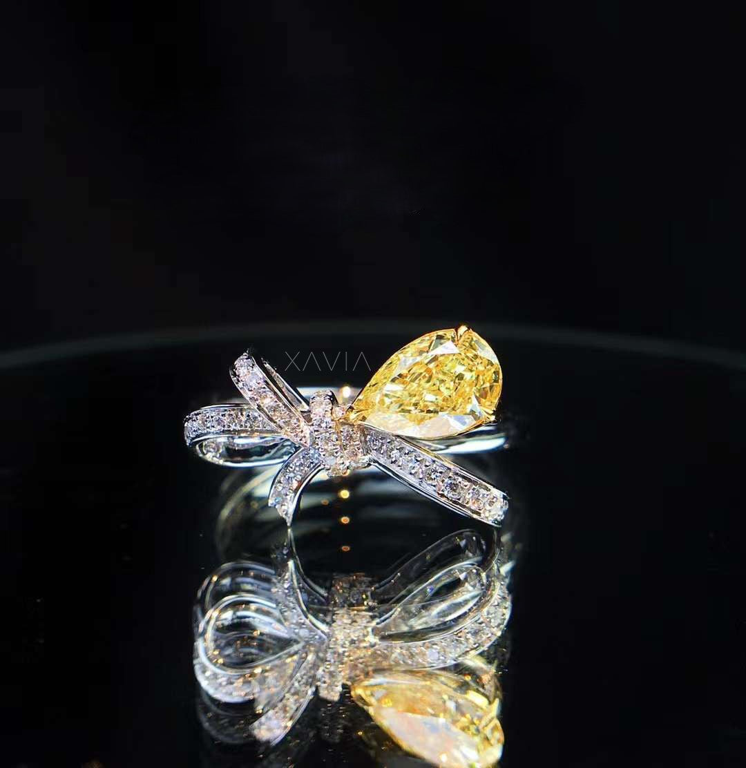 side profile angle of fancy yellow pear cut diamond bow-inspired engagement ring with pavé accents in high-polish band